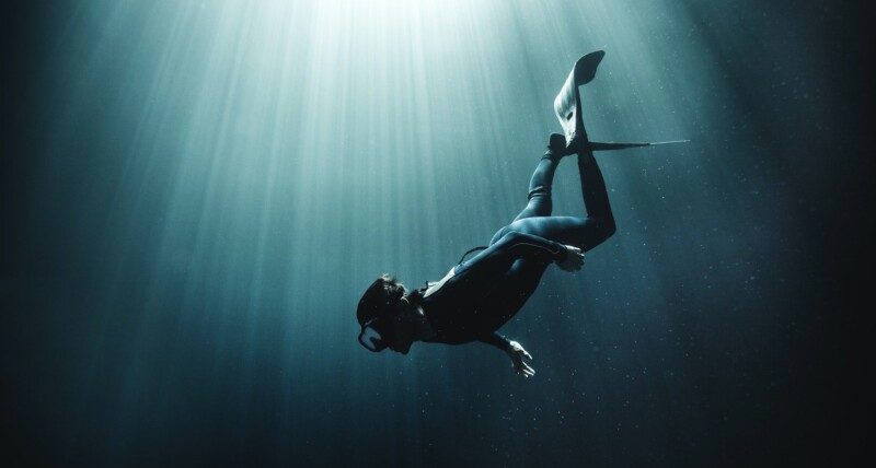 underwater-view-of-diver-wearing-wet-suit-and-flippers-sunlight-filtering-through-from-above-